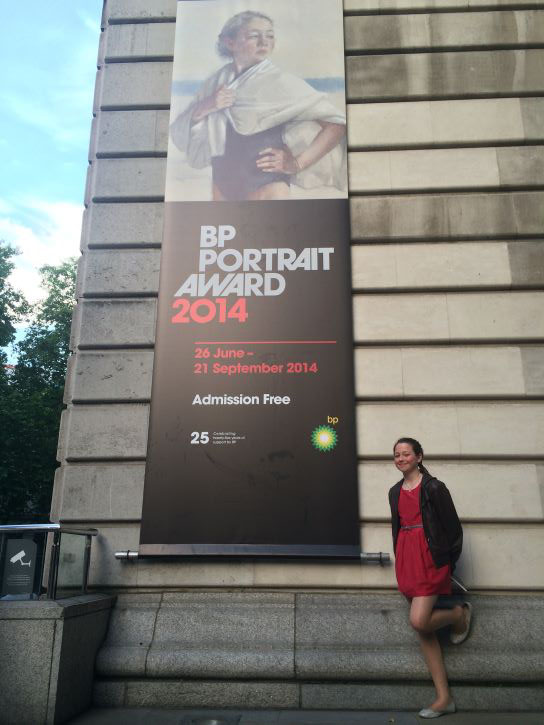 Lola Reid at the National Portrait Gallery, with the BP Portrait Prize exhibition banner