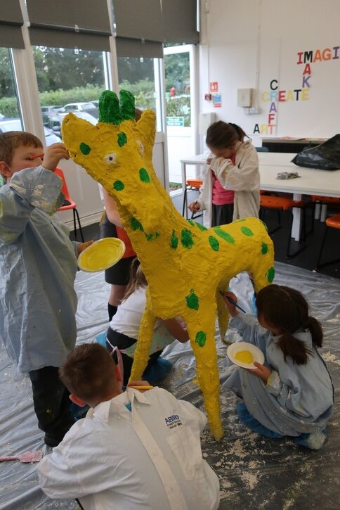 Children paint their giraffe sculpture