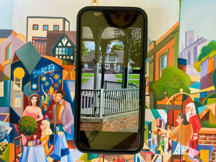 A phone photo of a park building laid over 'A Town on Millennium's Eve' by Tim Lloyd (b.1959)