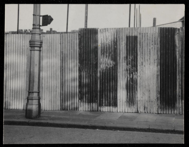 Black-and-white photograph of corrugated iron hoardings