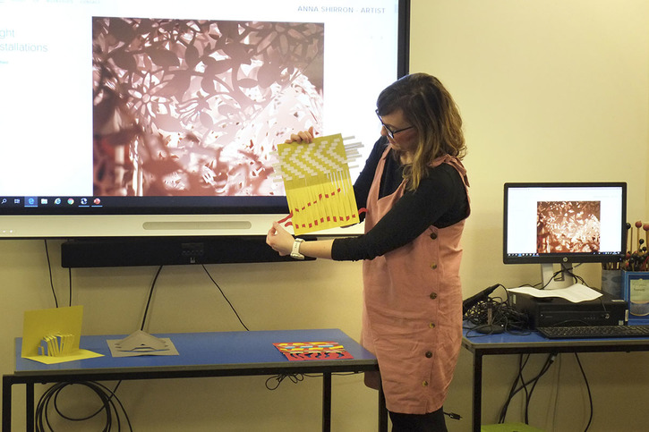 Anna Shirron showing students different ways of manipulating paper to create different effects