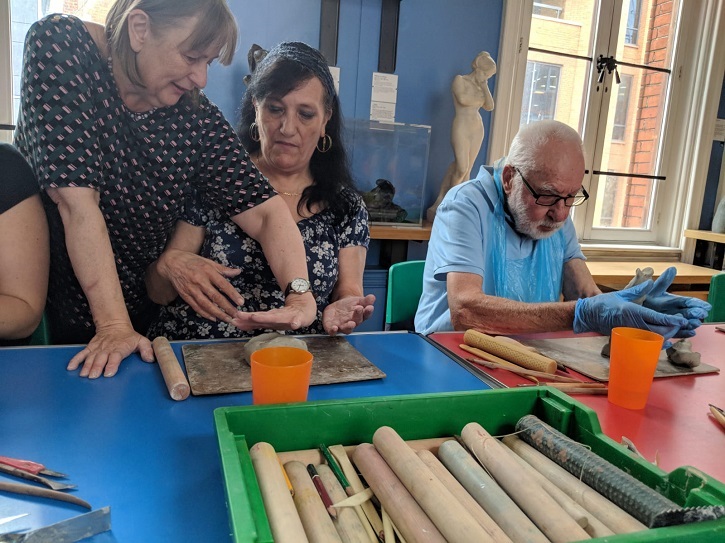 Artist Sally Booth supports VocalEyes workshop attendees to create clay sculptures at Reading Museum