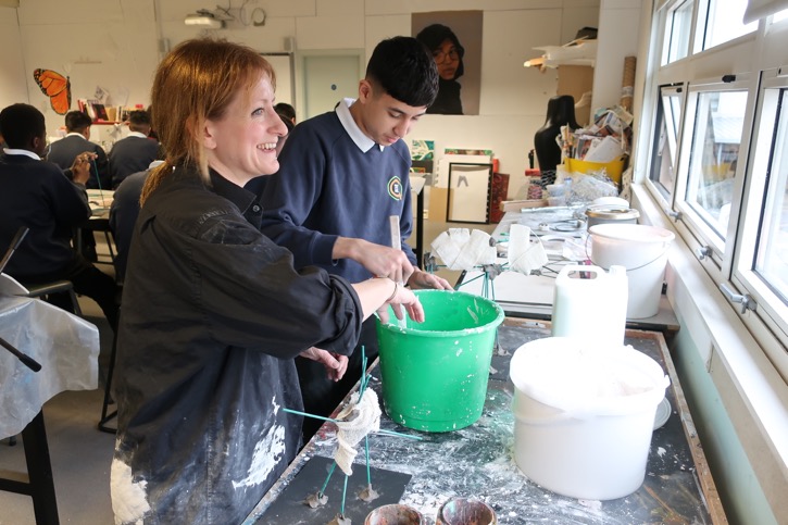 Zöe supports a student to wrap their sculpture in bandage and apply plaster