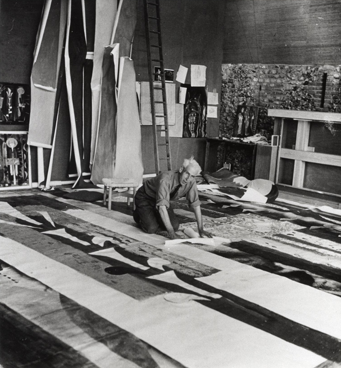 John Piper in his studio at Fawley Bottom, cutting the design for the stained glass window