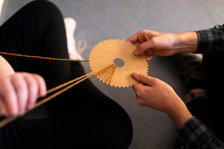 A student is supported to weave on a round loom