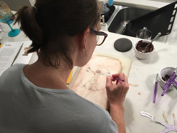 Sophie Shore painting Leonardo's Vitruvian Man on a cake