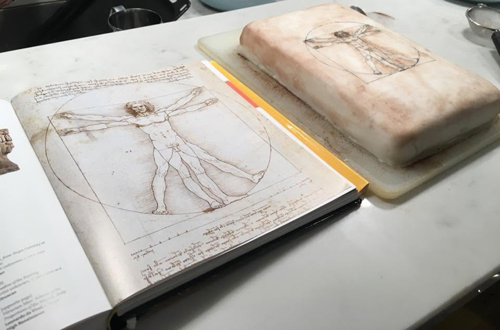 Vitruvian Man cake alongside the inspiration in an art history book