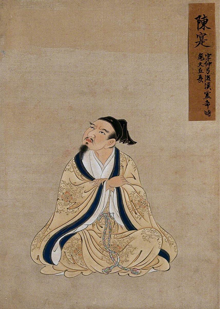A Seated Chinese Figure with Grey Beard Wearing Buff Coloured Robes with a Blue Border and a Black Cap