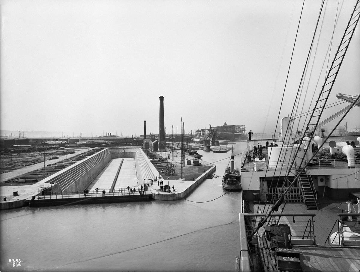 View aft to starboard poop deck while swinging and outfitting basin with Thompson Graving Dock and 'Titanic' in background