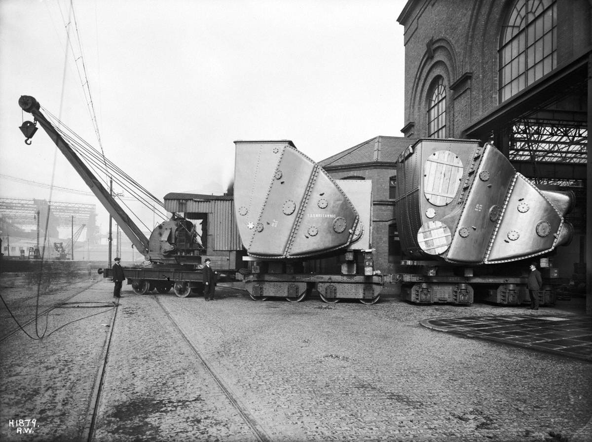 Condensers on trucks being towed out of shop by steam crane