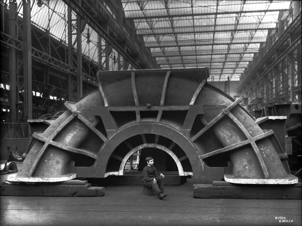 Turbine cover in erecting shop, with apprentice seated to give scale