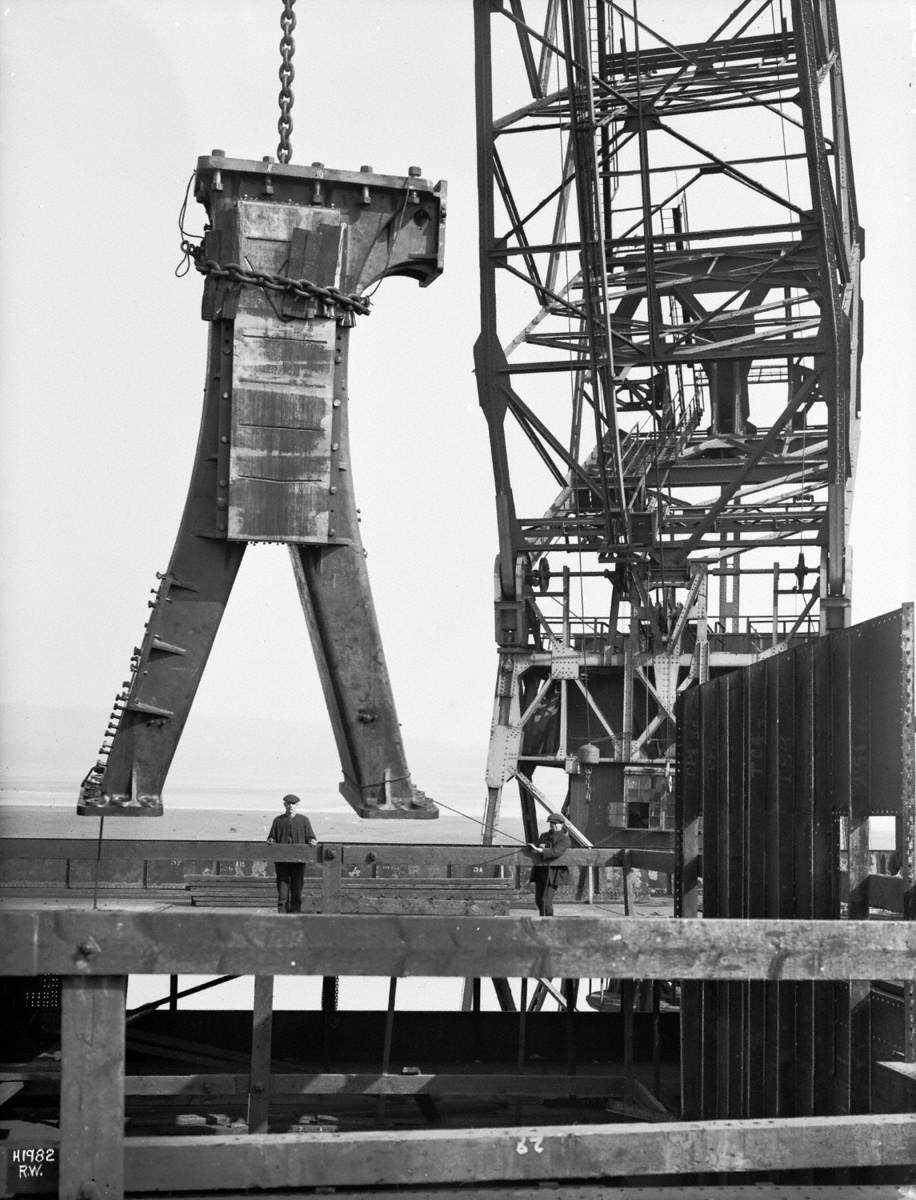Pillar of engine being lifted from dockside by floating crane