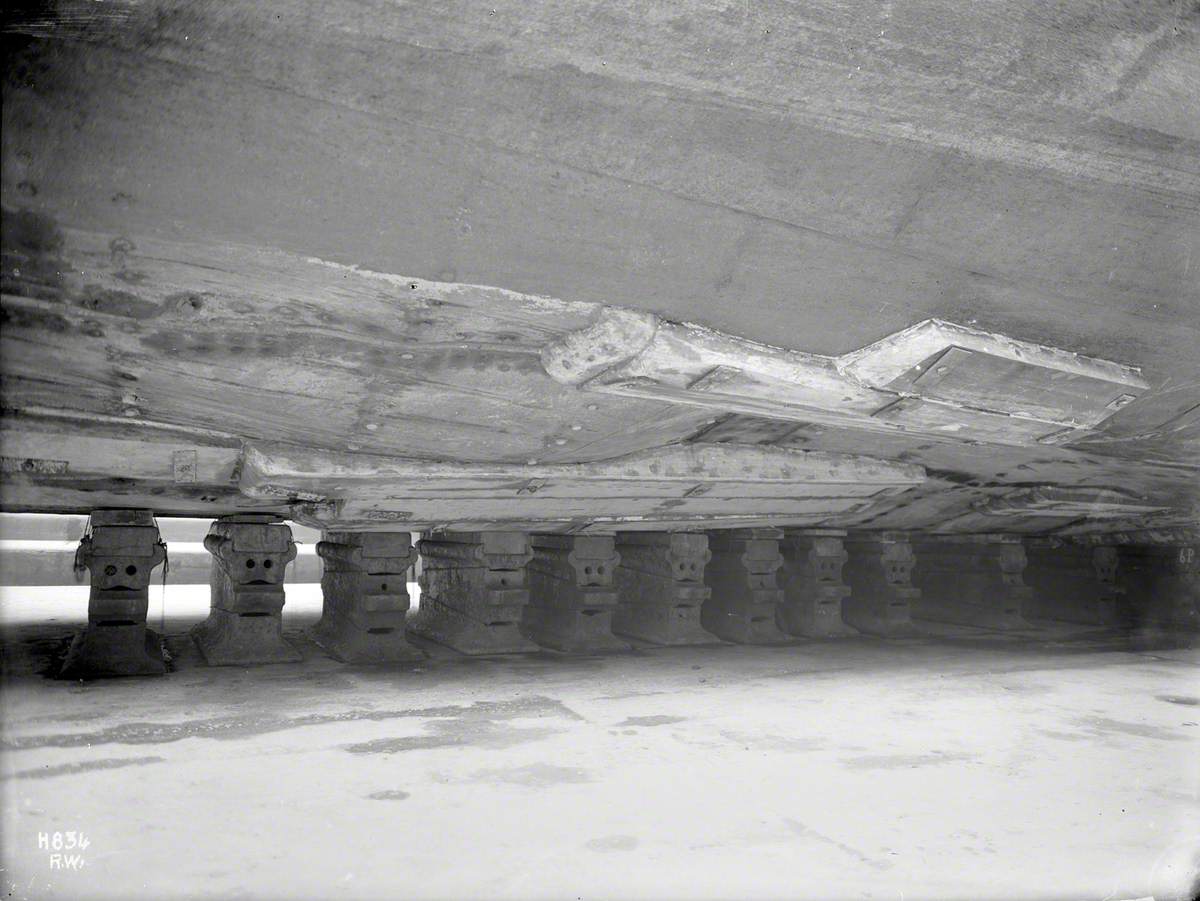 View of buckled plates on underside hull and temporary repairs, from floor of the dock