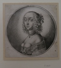 Half length portrait of a woman with curly hair drawn back from the forehead. She has a single row pearl necklace with a pearl drop