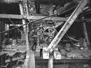 Drilling out port side propeller boss, with three men operating the drilling machine