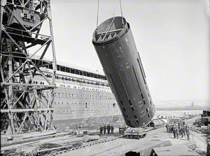 Number 3 funnel being hoisted to vertical position on dockside by floating crane