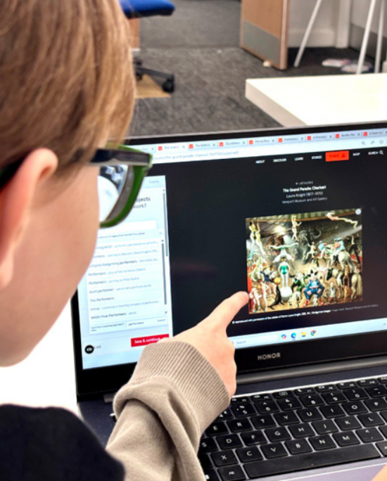 Two people sat in front of a laptop pointing at the image they are tagging on Art UK