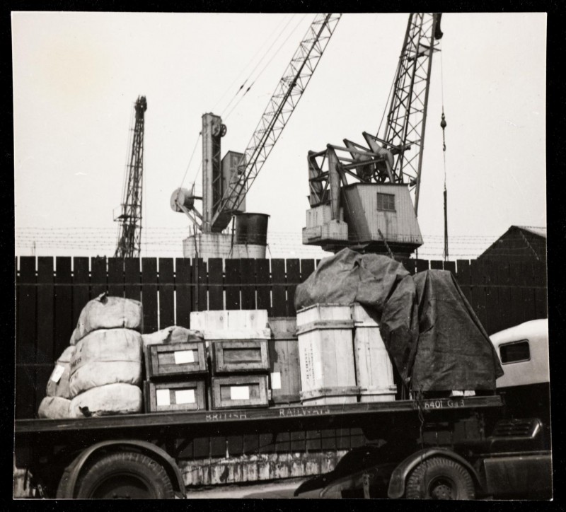 A flat bed lorry loaded with boxes and parcels with cranes in the back