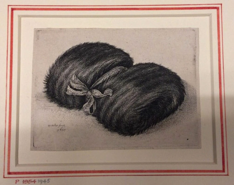 A dark muff lying diagonally, a ribbon is tied around the centre on which a bow is tied
