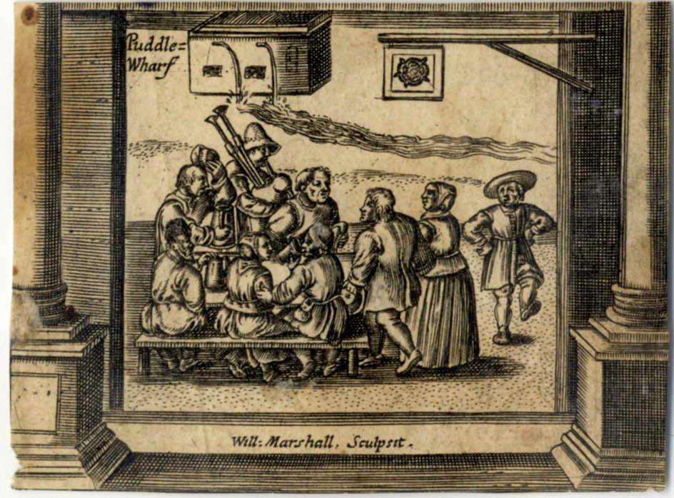 A group of men sitting around a table, one blowing a bagpipe